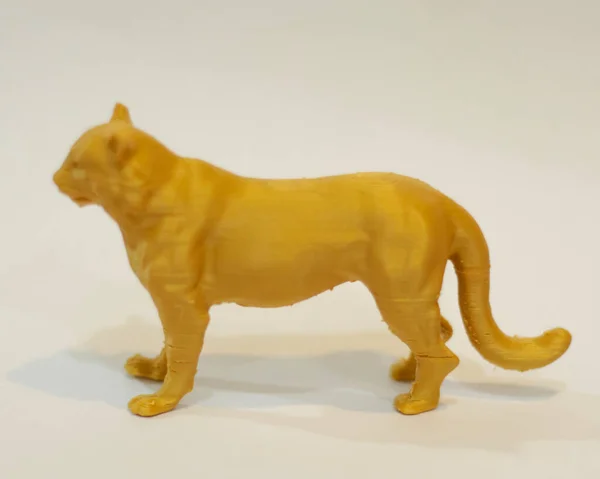 Cnc router in the shape of a yellow tiger. 3D design made of plastic. Miniature animals are suitable to be used as collections or room furniture. Laser cutting. Laser templates. Focus blur.