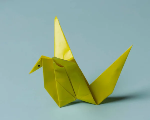 Blue bird-shaped origami on a blue background. Playing origami helps improve thinking power and increase children\'s creative abilities. Playing origami can be an alternative learning for children.