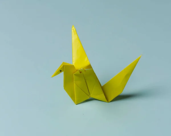 Blue bird-shaped origami on a blue background. Playing origami helps improve thinking power and increase children\'s creative abilities. Playing origami can be an alternative learning for children.