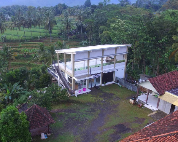 Aerial drone view of Indonesian countryside surrounded by green trees and some hills around it. Landscape aerial drone, drone footage, bird eye view, hight angle.