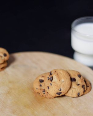 Sabahları çerez olarak çikolata parçacıklı bisküviler çocuklar arasında yaşlılığa kadar çok popülerdir. Bisküvi ve süt, yiyecek ve içeceğin mükemmel bir kombinasyonudur. Bisküvi modeli. Odak bulanıklığı.