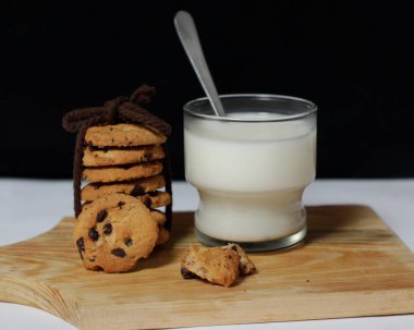 Sabahları çerez olarak çikolata parçacıklı bisküviler çocuklar arasında yaşlılığa kadar çok popülerdir. Bisküvi ve süt, yiyecek ve içeceğin mükemmel bir kombinasyonudur. Bisküvi modeli. Odak bulanıklığı.