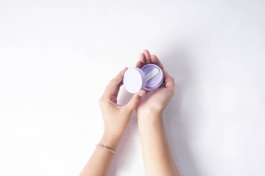 Görüntü beyaz bir arkaplan önünde nemlendirici tutan bir eli gösteriyor..                               