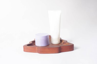 Görüntü, beyaz bir yüzey üzerinde duran ahşap bir kapta duran güneş kremi ve nemlendirici gösteriyor..                               