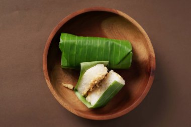 Bir lemper keki, kahverengi arka plana karşı ahşap bir kaseye yerleştirilir..                    