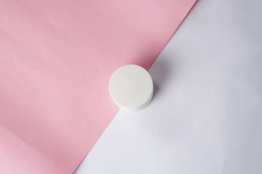 Beyaz bir Glad2Glow nemlendiricisi beyaz ve pembe arka plana yerleştirilir ve yumuşak ve kadınsı bir görünüm yaratır.                               