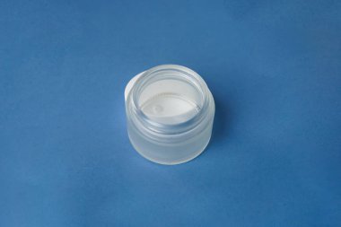 Beyaz bir nemlendirici kavanoz lacivert bir arka planda zarifçe oturur, zarafet ve derinlik hissi verir.                               