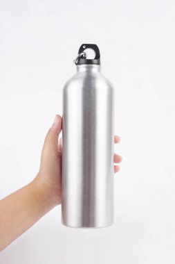 Gri içki şişesi temiz beyaz bir arka planda elle tutulur.                           