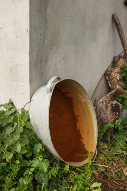 Ahır duvarına dayanmış eski bir metal ve paslı bir leğen.