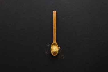 Koyu arkaplanda zencefilli ahşap bir kaşık. Yukarıdan görüntüle.