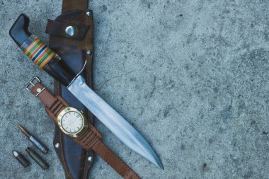 Av bıçağı, deri kılıf, kartuş ve betonun üzerinde deri kayış olan klasik kol saati. Açık havada turist ekipmanı. Üst Manzara. Yakın plan. Boşluğu kopyala.