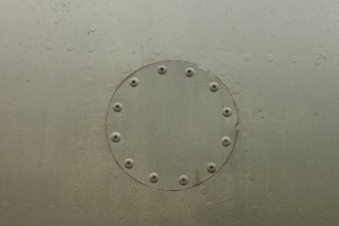 Eski bir kamuflaj yüzeyi perçinlenmiş yuvarlak kapaklı ve askeri bir uçağın üzerinde yeşil renk var. Eski bir jet uçağının gövdesinin parçası.