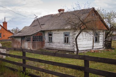 Ağaçların arasında terk edilmiş eski ahşap bir ev. Kırsal ilkbahar manzarası.