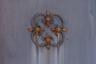 Eski ve paslı, metal bir çitin üzerinde dövülmüş bir dekor. Yakın plan.