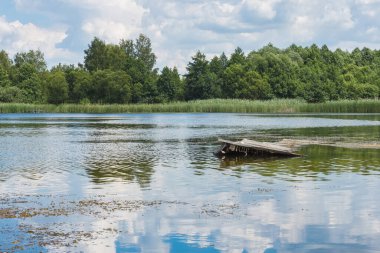 Mavi gökyüzü ve beyaz bulutlarla güneşli bir günde göl. Göldeki bulutların yansıması. Yaz