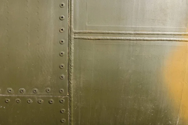 Details of the fuselage of an old aircraft. Old camouflage surface with exfoliated paint and rivets on a military aircraft.