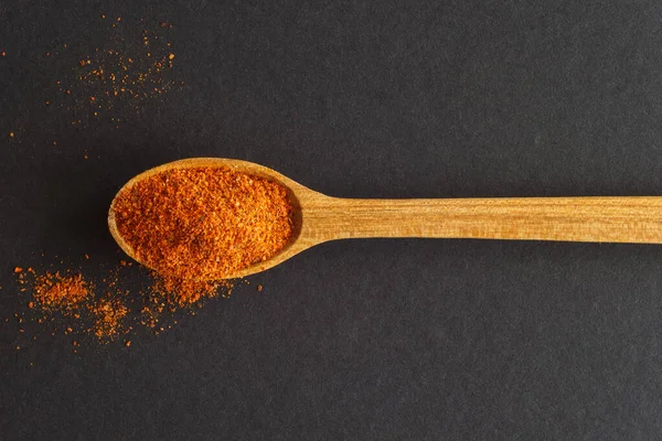 Koyu arka planda acı biberli ahşap bir kaşık. Yukarıdan görüntüle