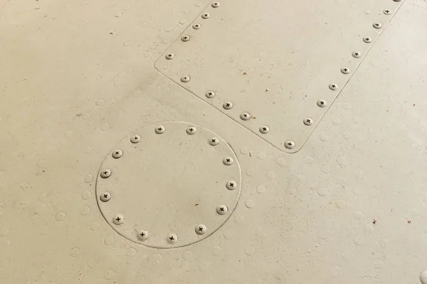 Details of the fuselage of an old aircraft. Camouflage surface with paint and rivets on a military aircraft.