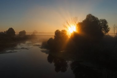 Güneşin doğuşu sisli nehirde