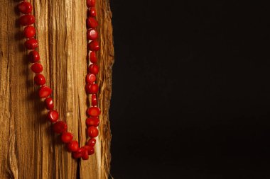 Ahşap bir yüzeyde kırmızı mercan kolye. Metin için boşluk olan koyu arkaplan. 