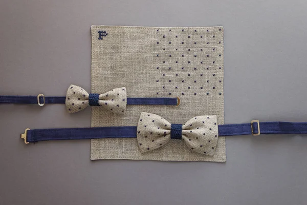 Bow ties and pocket square with embroidery. Made of linen fabric. Gray background. Top view.