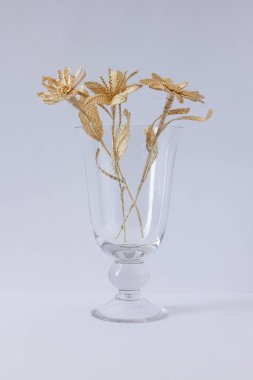 Beyaz arka planda samandan yapılmış bir buket çiçekli cam bir vazo.