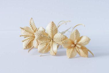 Beyaz arka planda üç çiçek samandan yapılır.