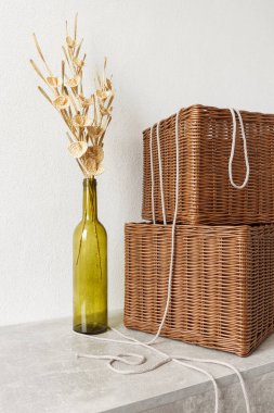 Çiçekler boş bir şişe ve hasır sepetlerde beyaz bir zemin üzerinde samandan yapılmıştır.