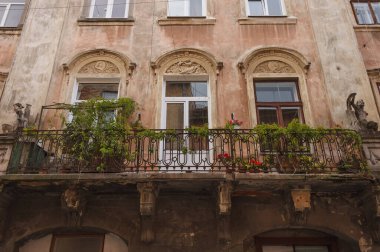 Evin girişinde paslı, çit dövmeli ve peyzajlı bir balkon var. Eski evin ön cephesindeki heykel ayrıntıları. Parça. Lviv, Ukrayna
