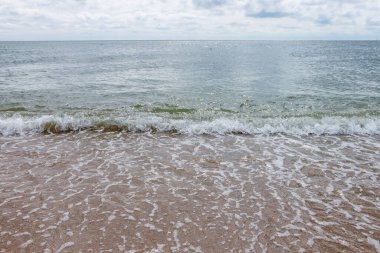 Güneşli bir günde gökyüzünde bulutlarla Karadeniz. Beyaz köpüklü dalgalar ve kumlu kıyılar