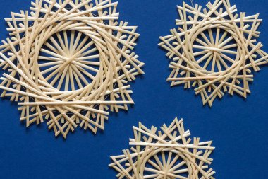 Snowflakes are made of straw on a blue background. Christmas decor. Top view. Straw weaving. Lutsk, Ukraine
