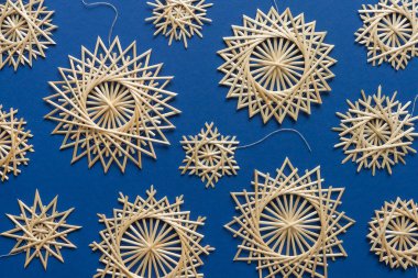 Snowflakes are made of straw on a blue background. Christmas decor. Top view. Straw weaving. Lutsk, Ukraine