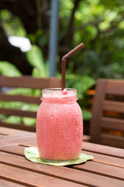 Een glas strawberry smoothie op een houten achtergrond — Stockfoto