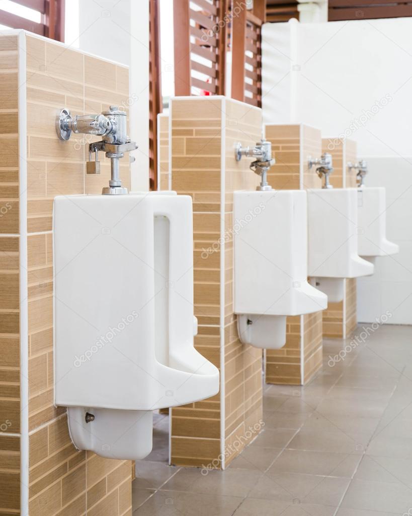 White urinals with ceramic tile on wall.