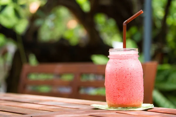 Een glas strawberry smoothie op een houten achtergrond Stockfoto