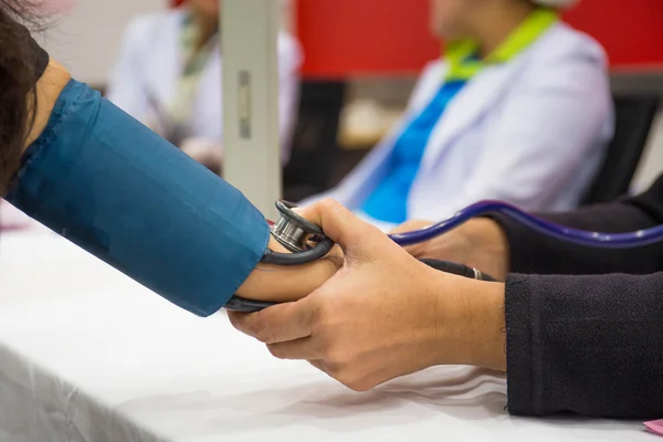 Nahaufnahme einer Krankenschwester, die mit Stethoscop den Blutdruck kontrolliert — Stockfoto