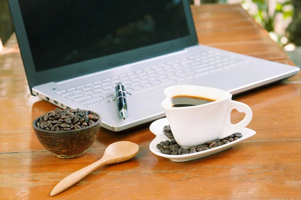 Taza de café y portátil en mesa de madera. —  Fotos de Stock
