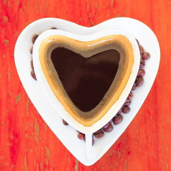 Kahve fincanı kırmızı zemin üzerinde kalp şeklinde — Stok fotoğraf