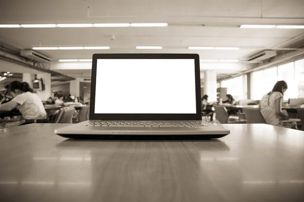 Portátil con pantalla en blanco en la mesa en la biblioteca — Foto de Stock