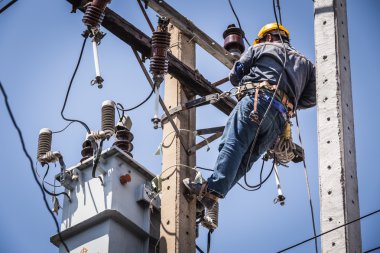 Elektrikçi elektrik direğine asılı
