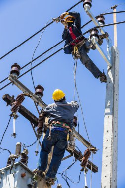 Elektrik direği üzerinde çalışan elektrikçiler