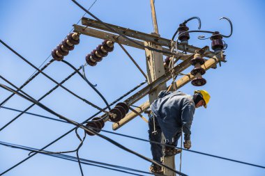 Elektrikçi elektrik direğine asılı