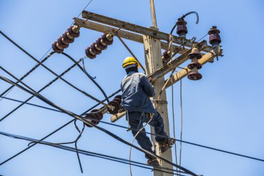 Elektrikçi elektrik direğine asılı