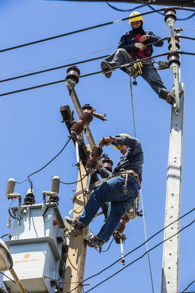 Elektrik direği üzerinde çalışan elektrikçiler