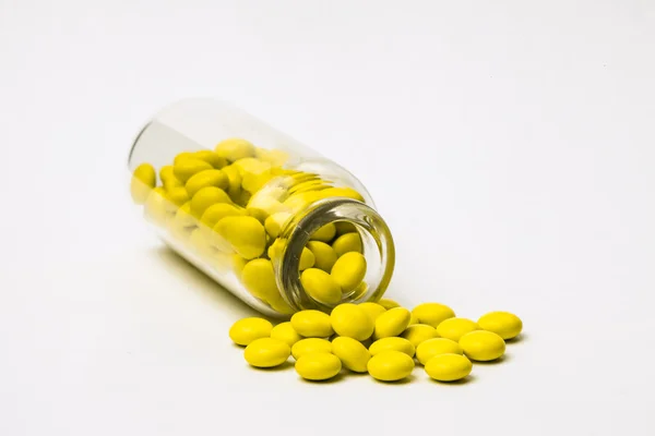 Перевернутый стеклянный флакон с разбросанными маленькими желтыми таблетками Стоковое Изображение