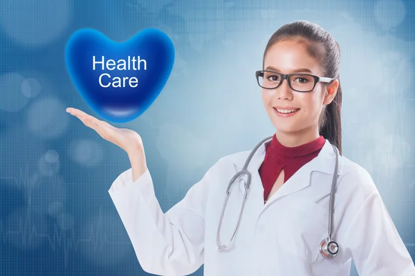 Female doctor holding heart with health care sign on medical background. — Stock Photo, Image
