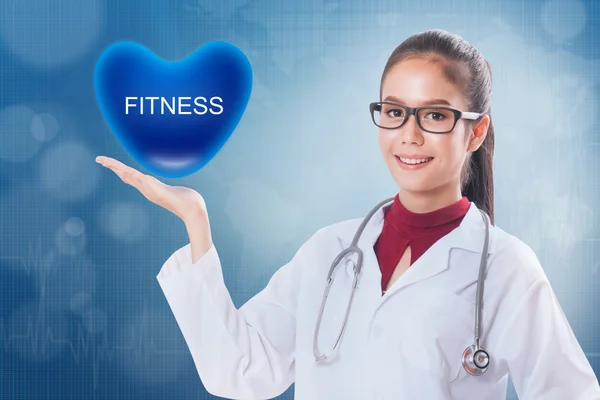 Médico femenino sosteniendo el corazón con signo de aptitud en el fondo médico . — Foto de Stock