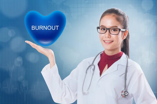 Ženský lékař drží srdce znakem vyhoření na lékařské vzdělání. — Stock fotografie