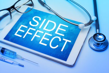 Arka planda tıbbi ekipman bulunan tablet ekranında yan etki sözcüğü