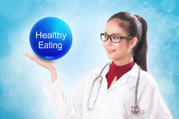 Médico femenino sosteniendo bola de cristal azul con signo de alimentación saludable en el fondo médico . — Foto de Stock